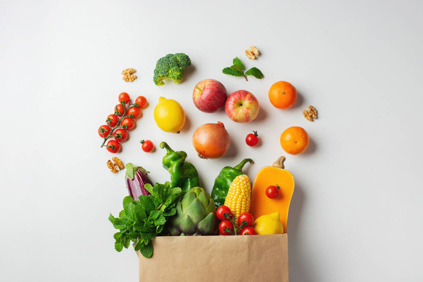 Levering gezond voedsel achtergrond. Gezond veganistisch vegetarisch voedsel in papieren zak groenten en fruit op wit. Winkelen supermarkt en schoon veganistisch eetconcept. - Foto, afbeelding