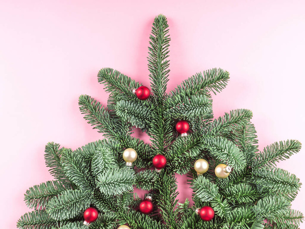 Weihnachtsbaum-Fichtenzweig mit roten Kugeln auf rosa - Foto, Bild