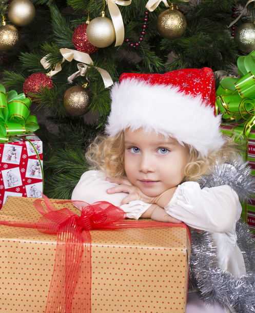 cute little girl in Santa's hat with big Christmas gift - 写真・画像