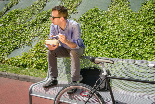 Nuori liikemies syömässä lounastauolla ulkona
 - Valokuva, kuva