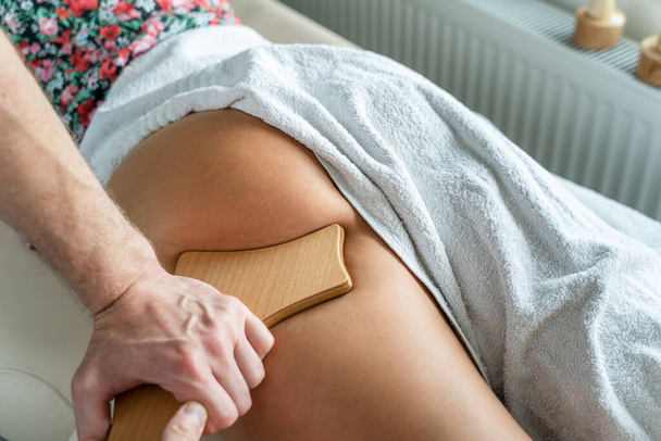 Крупним планом на спині невідомої жінки, яка має масаж мадеротерапії, антицелюлітне лікування професійним терапевтом, який тримає дерев'яні інструменти в руках в студії або салоні з копіювальним простором
 - Фото, зображення