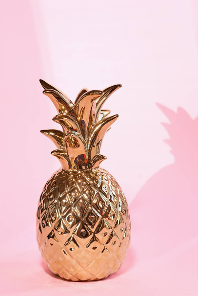 Золотой ананас для домашнего декора на бледно-розовом фоне - Фото, изображение