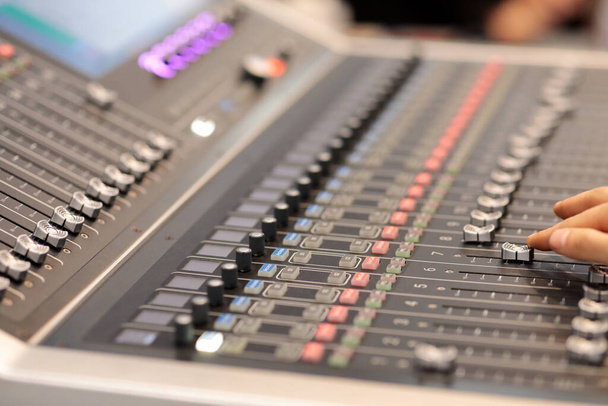 Hand of sound engineer adjusting faders on an audio mixing console. Selective focus. - Photo, Image