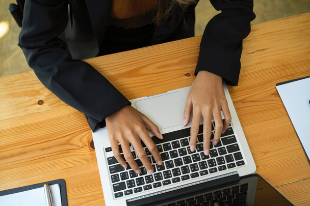 Close-up bovenaanzicht beeld van zakenvrouw of vrouwelijke werknemer typen op laptop computer toetsenbord op haar bureau. - Foto, afbeelding