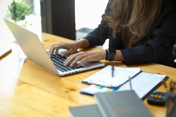 Immagine ravvicinata di una donna d'affari che utilizza un computer portatile per il suo incarico in ufficio. - Foto, immagini