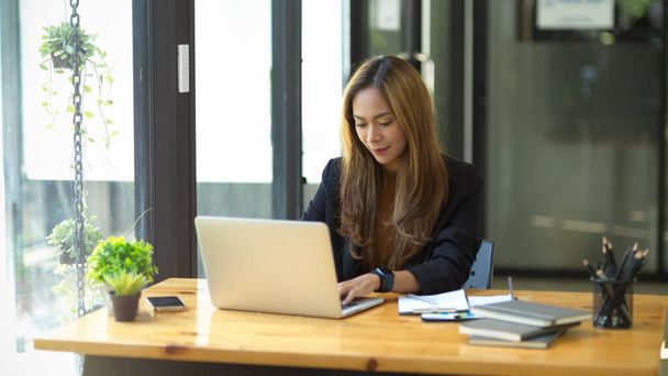Schöne asiatische junge Mitarbeiterin oder Geschäftsfrau mit Laptop-Computer in ihrem Büro. - Foto, Bild
