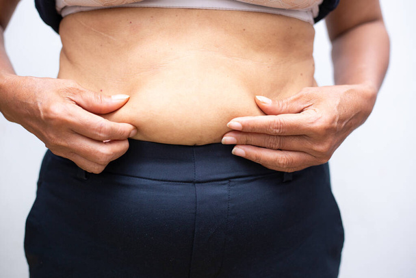 Жінки тримають жирний великий живіт на білому тлі здорового харчування концепції
 - Фото, зображення