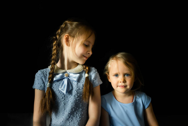 Portrait of two sisters on a dark background. Family taking. - Foto, Bild
