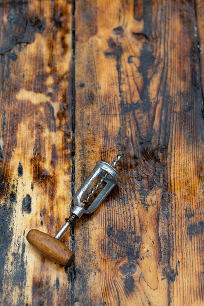 The corkscrew for opening wine lies on a dark brown wooden background. - Foto, afbeelding