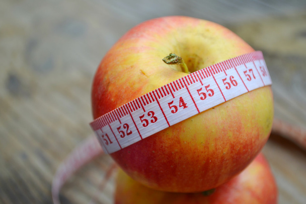 Concepto de dieta con manzana roja y cinta métrica azul en mesa de madera
 - Foto, Imagen