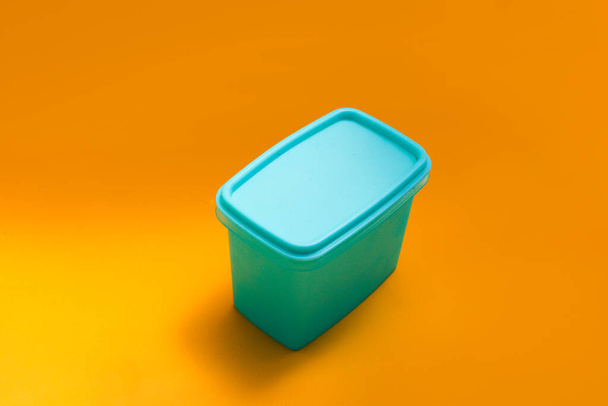 Plastic lunchbox (pot of container) geïsoleerd op oranje achtergrond - Foto, afbeelding