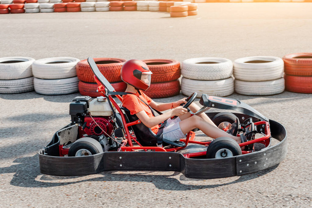 Happy teenage boy driving a go kart car around the cartodrome. Hobbies and extreme sports for a child and the fulfillment of a dream - Foto, imagen