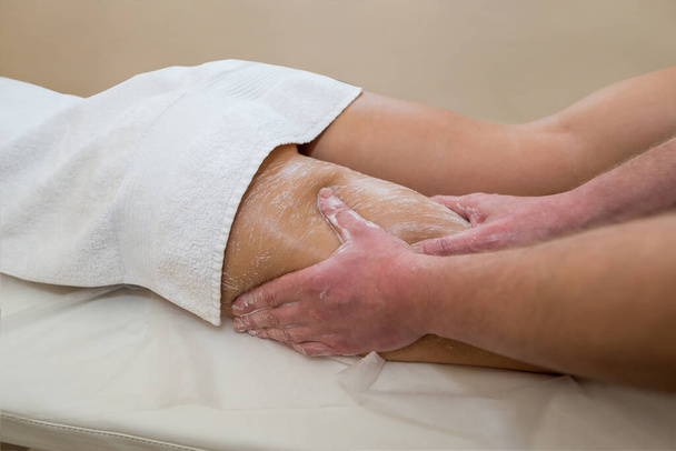 Schönheitsbehandlungen im Wellnessbereich. Massagetherapeutin schrubbt die Beine des Mädchens. Schrubben der Beine im Wellnessbereich. - Foto, Bild
