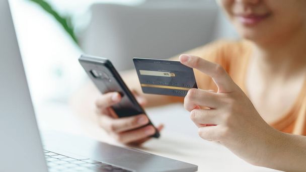 Mladá žena držící kreditní kartu a používající smartphone pro online nakupování, internetové bankovnictví, e-commerce, utrácení peněz, práce z domova koncept - Fotografie, Obrázek