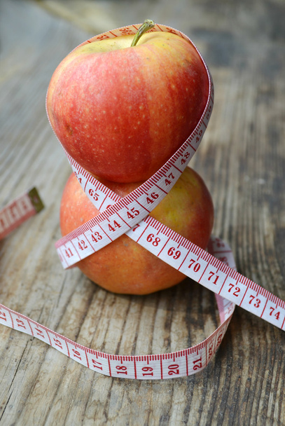 Concepto de dieta con manzanas rojas y amarillas y cinta métrica blanca en mesa de madera
 - Foto, imagen