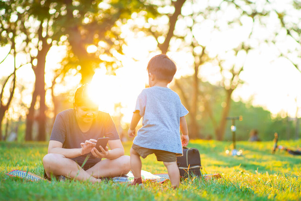 Onnellinen lapsi ja hänen äitinsä pitää hauskaa ulkona vihreällä nurmikentällä, äiti halailee lastaan puistossa kävelyn aikana. - Valokuva, kuva