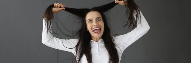 Crazy woman holds hair and makes grimaces closeup - Foto, Bild