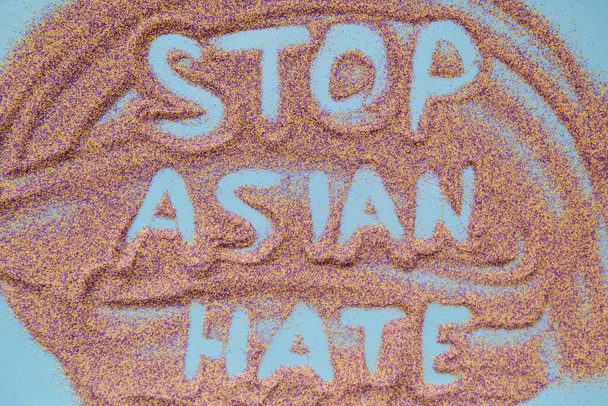 Остановить азиатский текст ненависти, написанный от руки на красочном песке. Настоящая проблема. Высокое качество фото - Фото, изображение