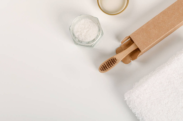Cepillo de dientes de bambú de producto natural con toalla blanca y sal para cepillarse los dientes en una olla pequeña. Eco concepto de baño amigable. No hay concepto plástico - Foto, Imagen
