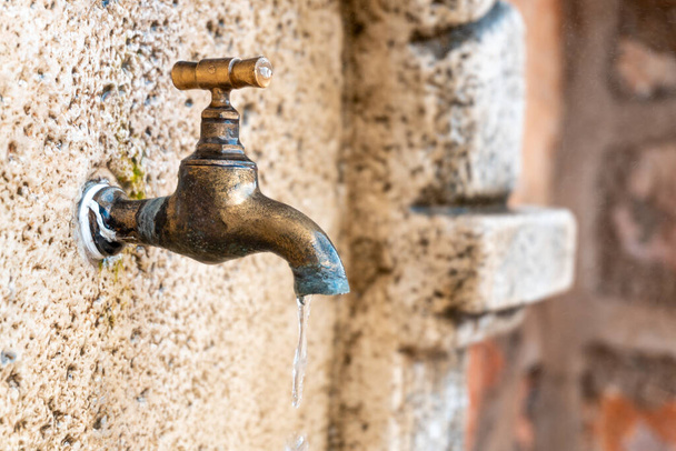 A closeup shot of an old tap on the wall outdoors in the street - Foto, imagen
