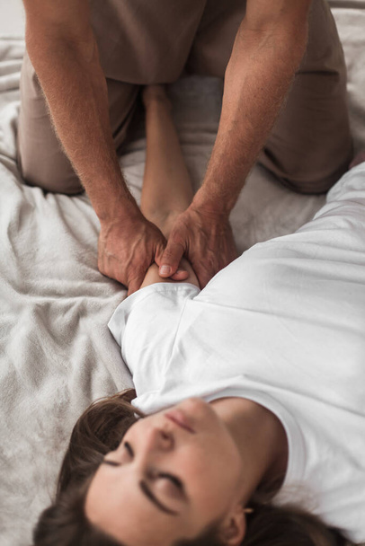 A middle-aged Caucasian masseur and a woman doing Japanese arm massage exercises on a mat at home - Φωτογραφία, εικόνα