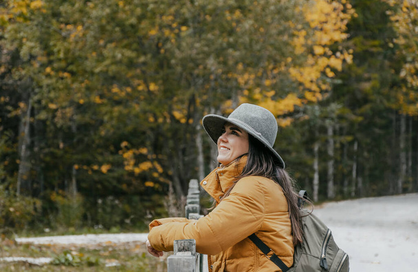 A Caucasian woman with a grey hat, and a backpack in an autumn park, Croatia - 写真・画像