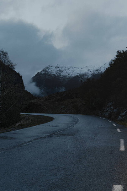 A vertical shot of an empty road passing through hills on a foggy day - Fotoğraf, Görsel