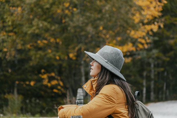 A Caucasian woman with a grey hat, and a backpack in an autumn park, Croatia - Photo, Image