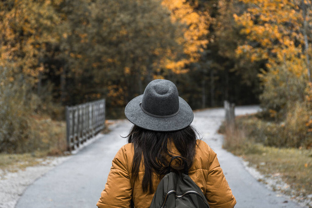 A Caucasian woman with a grey hat, and a backpack in an autumn park, Croatia - Fotó, kép