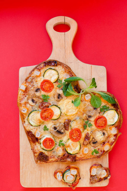 Szív alakú pizza paradicsommal, zöldséggel és sajttal Valentin-napra a háttérben. A romantikus szerelem kreatív ételkoncepciója. Felülnézet, lapos fektetés. - Fotó, kép