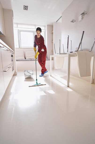 Focused experienced Caucasian cleaning lady mopping kitchen - Foto, immagini