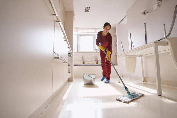 Concentrated uniformed professional janitor doing wet cleaning - Fotoğraf, Görsel