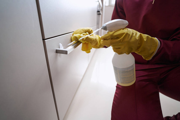 Janitor sprinkling detergent on piece of furniture - Foto, Imagen