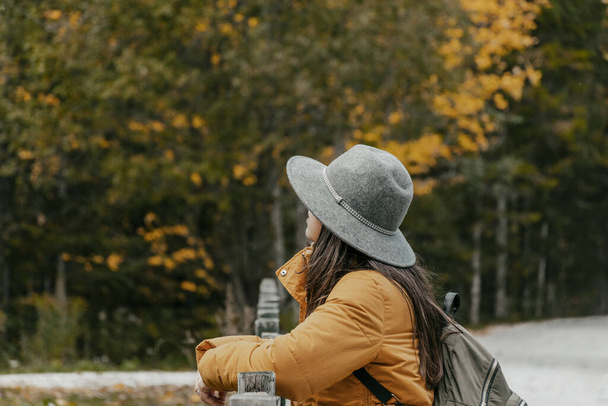 A Caucasian woman with a grey hat, and a backpack in an autumn park, Croatia - Foto, Imagen