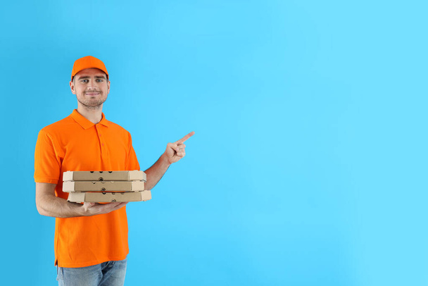 Delivery man holds pizza on blue background - Фото, зображення