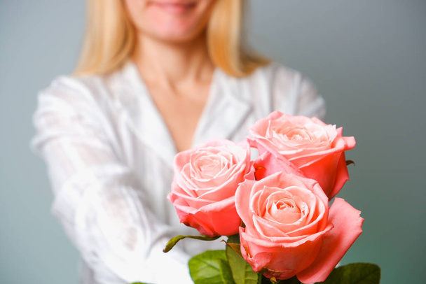 Woman in white shirt holding tender pink Rose Flower in Hands. Close up view on flower. - Foto, Bild