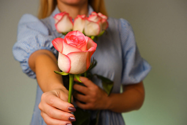 Frau im blauen Kleid schenkt dem Mann eine zarte rosafarbene Rosenblume. Nahaufnahme der Hände mit einer Rose. Romantik, Liebe. - Foto, Bild