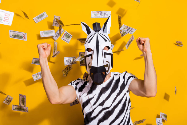 Photo of freak incognito guy in zebra mask fists up win billion salary money fly isolated over bright yellow color background - Fotografie, Obrázek