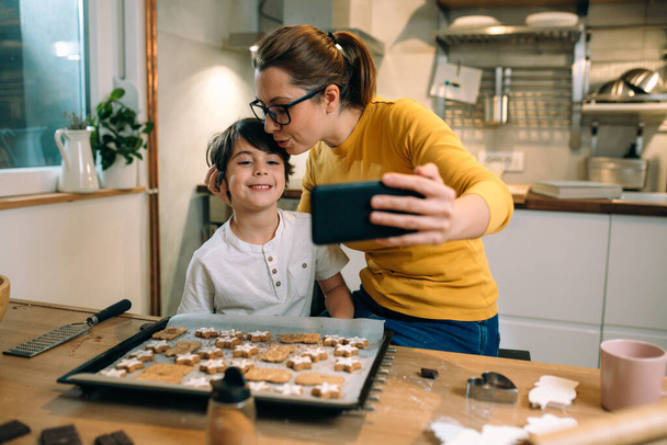 mother and child in kitchen, preparing cookies - 写真・画像
