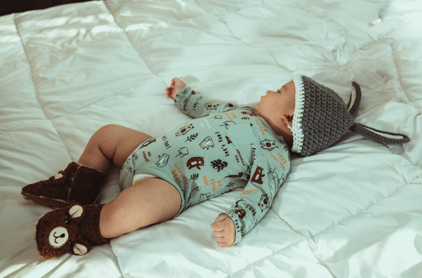 An adorable newborn baby with a knitted hat lying on a bed - Foto, immagini