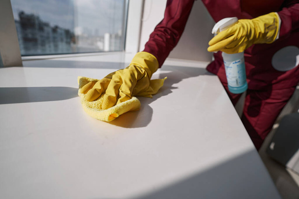 Worker in rubber gloves cleaning sill with microfiber cloth - Foto, Imagen