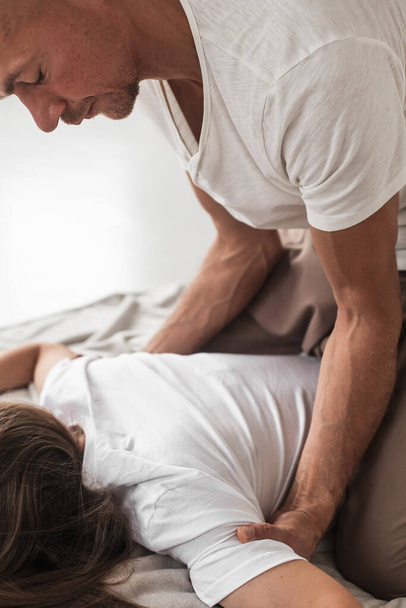 A middle-aged Caucasian bald masseur and a woman doing Japanese massage exercises on a mat at home - Zdjęcie, obraz