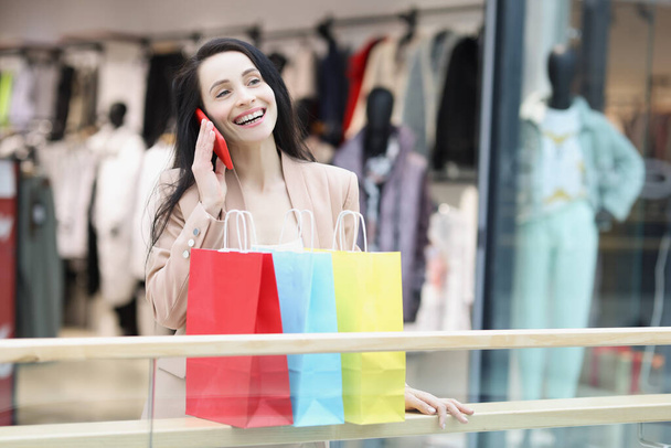 Mladá žena shopaholic s úsměvem a říct přátelům na volání o prodeji - Fotografie, Obrázek