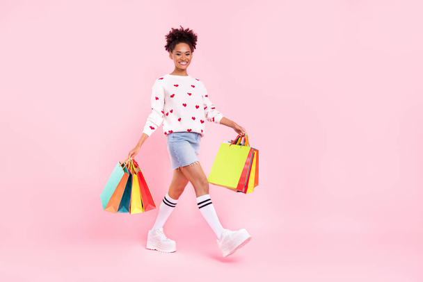Full body profile photo of cute brunette millennial lady go shopping wear pullover skirt socks sneakers isolated on pink background - Foto, immagini