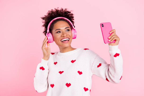 Photo of young african girl have fun listen radio earphones look empty space use mobile isolated over pink color background - 写真・画像