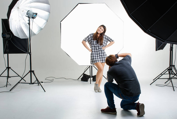 Photographer and cout young teen Asian model working in modern lighting studio with many kinds of flash and accessories. Stock shooting for commercial photo and contents concept. - Photo, image