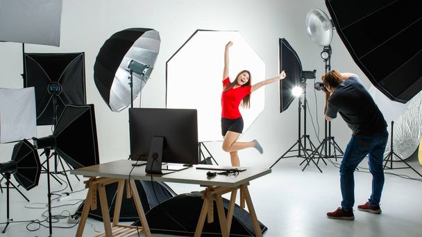 Photographe et cout jeune modèle asiatique adolescent travaillant dans un studio d'éclairage moderne avec de nombreux types de flash et accessoires. Stock shooting pour photo commerciale et concept de contenu. - Photo, image