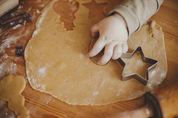 Cute little girl making christmas cookies on messy table, close up. Adorable toddler daughter helping mother and cutting dough for gingerbread cookies. Lovely moments, holiday preparations - Photo, Image