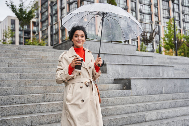 Cheerful pretty girl holding umbrella while strolling outside - Foto, immagini