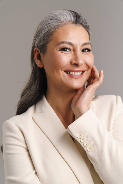 Mature woman with white hair smiling and looking at camera isolated over grey background - Foto, immagini